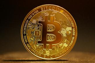 a golden bitcoin sitting on top of a table by Kanchanara courtesy of Unsplash.